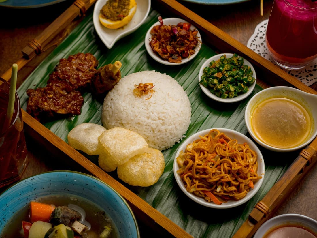 Nasi dengan lauk lengkap di atas daun pisang